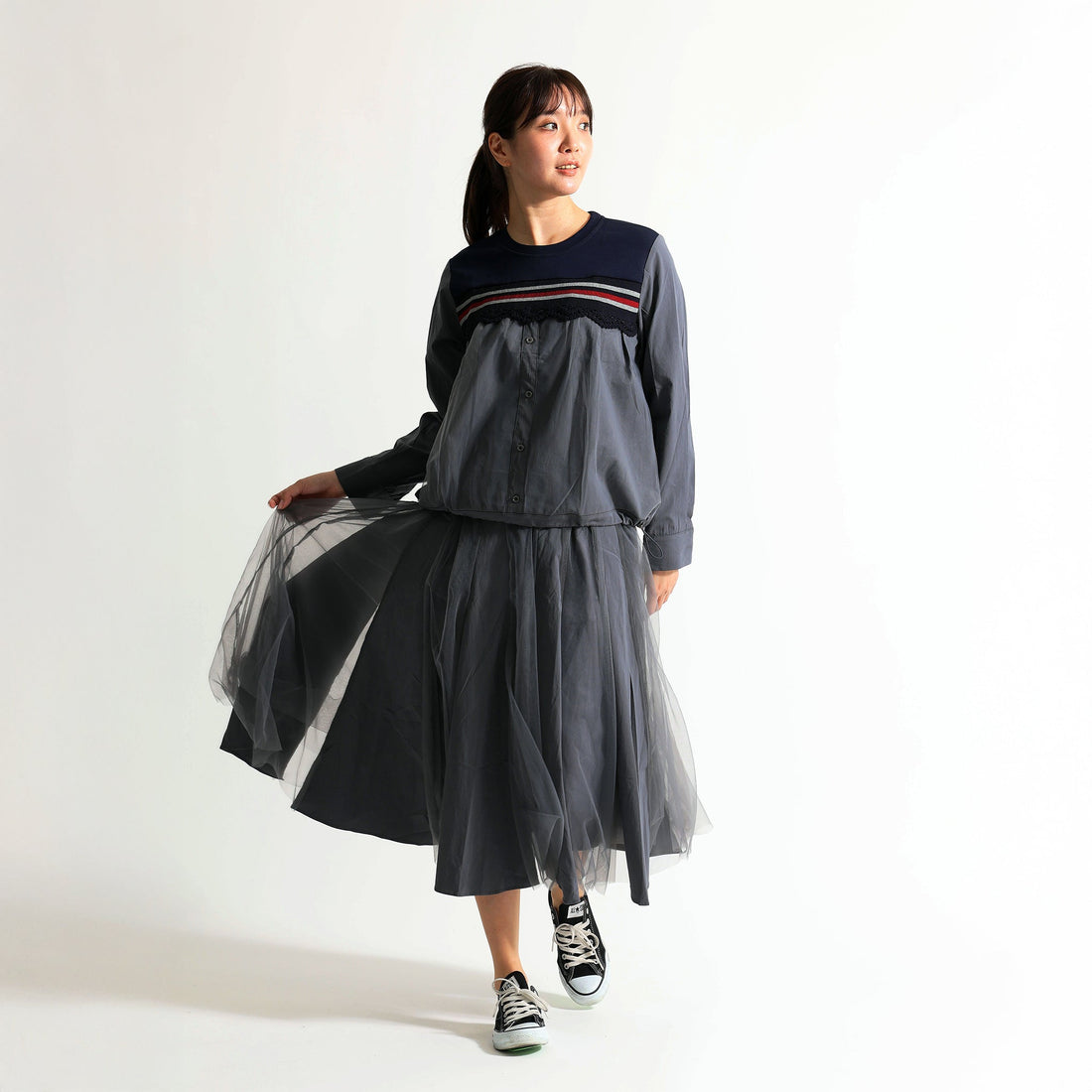 Soyombo（ソヨンボ）の異素材切り替えトップスとグレーのチュールスカートを着用した女性のスタイリング。胸元のラインテープとフリルがアクセントのトップスに、軽やかなチュールを合わせたワントーンコーデ。